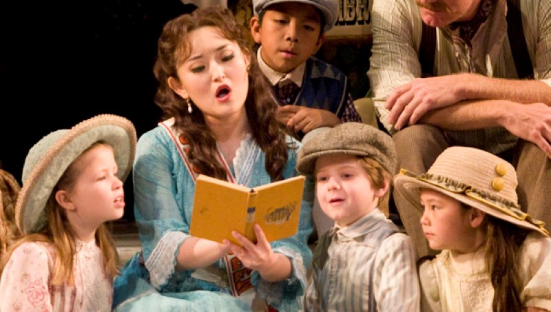 Woman singing to children from a song book