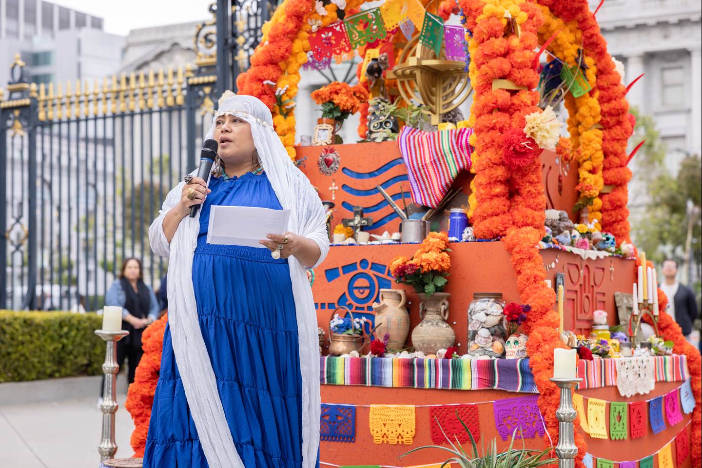 Performer speaking in front of an altar where we will hold a unique, multicultural, ritual ceremony that dives deep into the celebrations of the stages of life and death.  