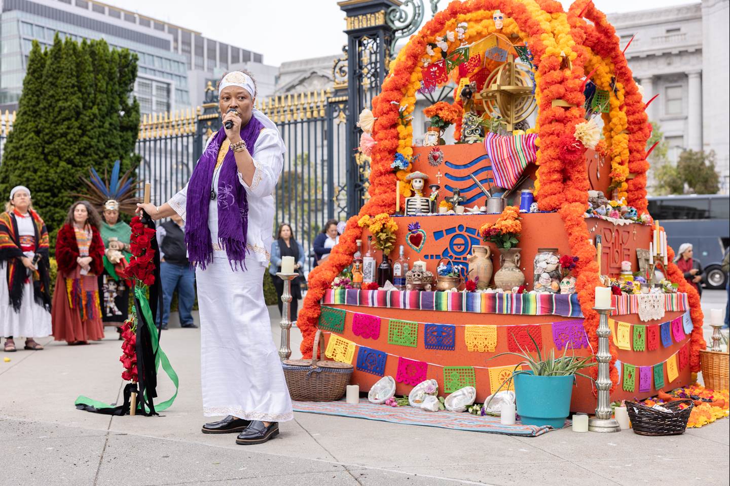 Performer speaking at an altar where we will hold a unique, multicultural, ritual ceremony that dives deep into the celebrations of the stages of life and death.  