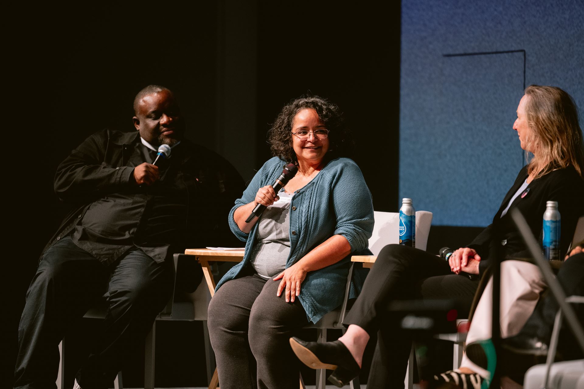 A group of panelists on a stage with microphones