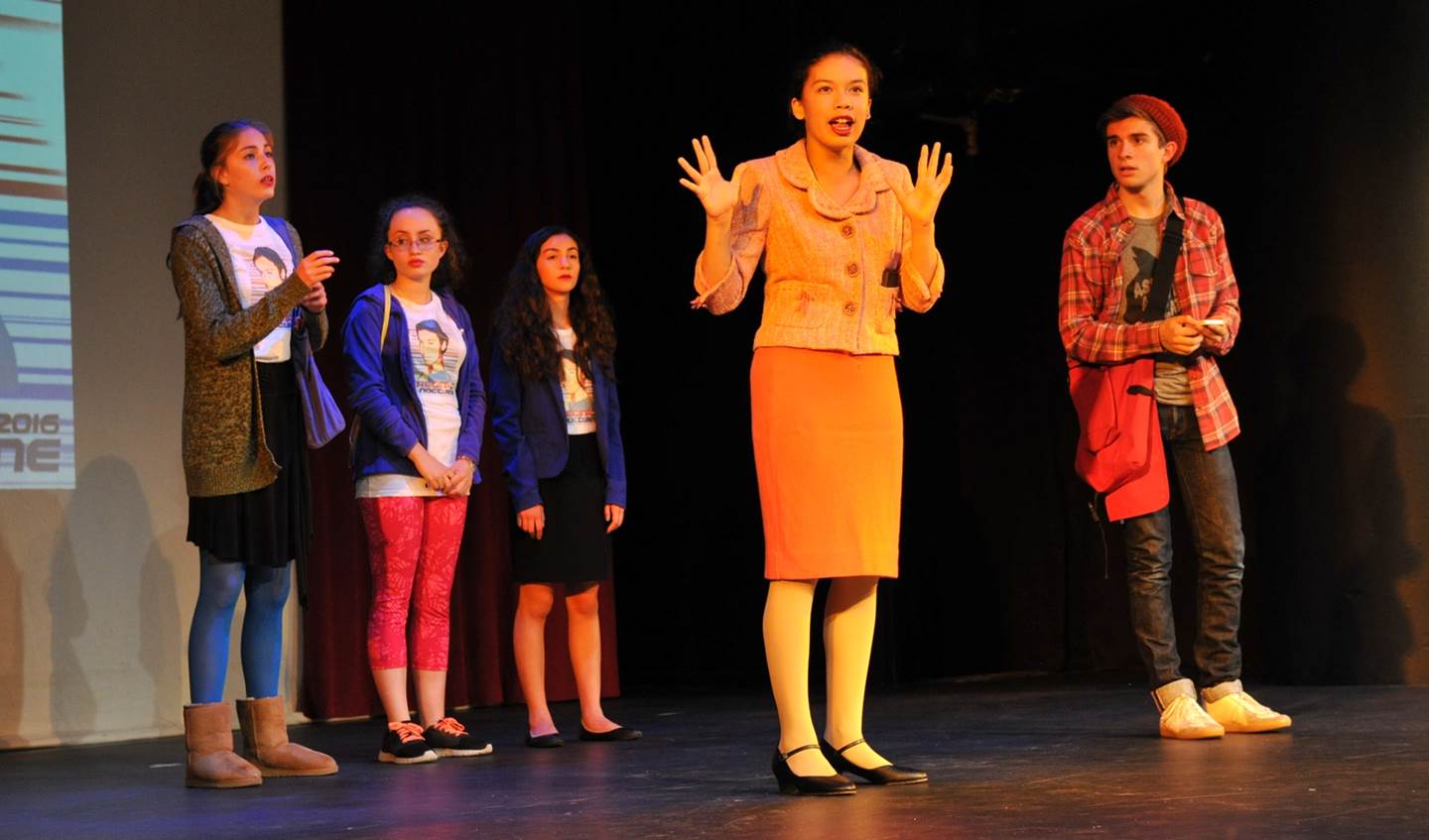 A young woman is talking towards the audience while other students stand behind her.