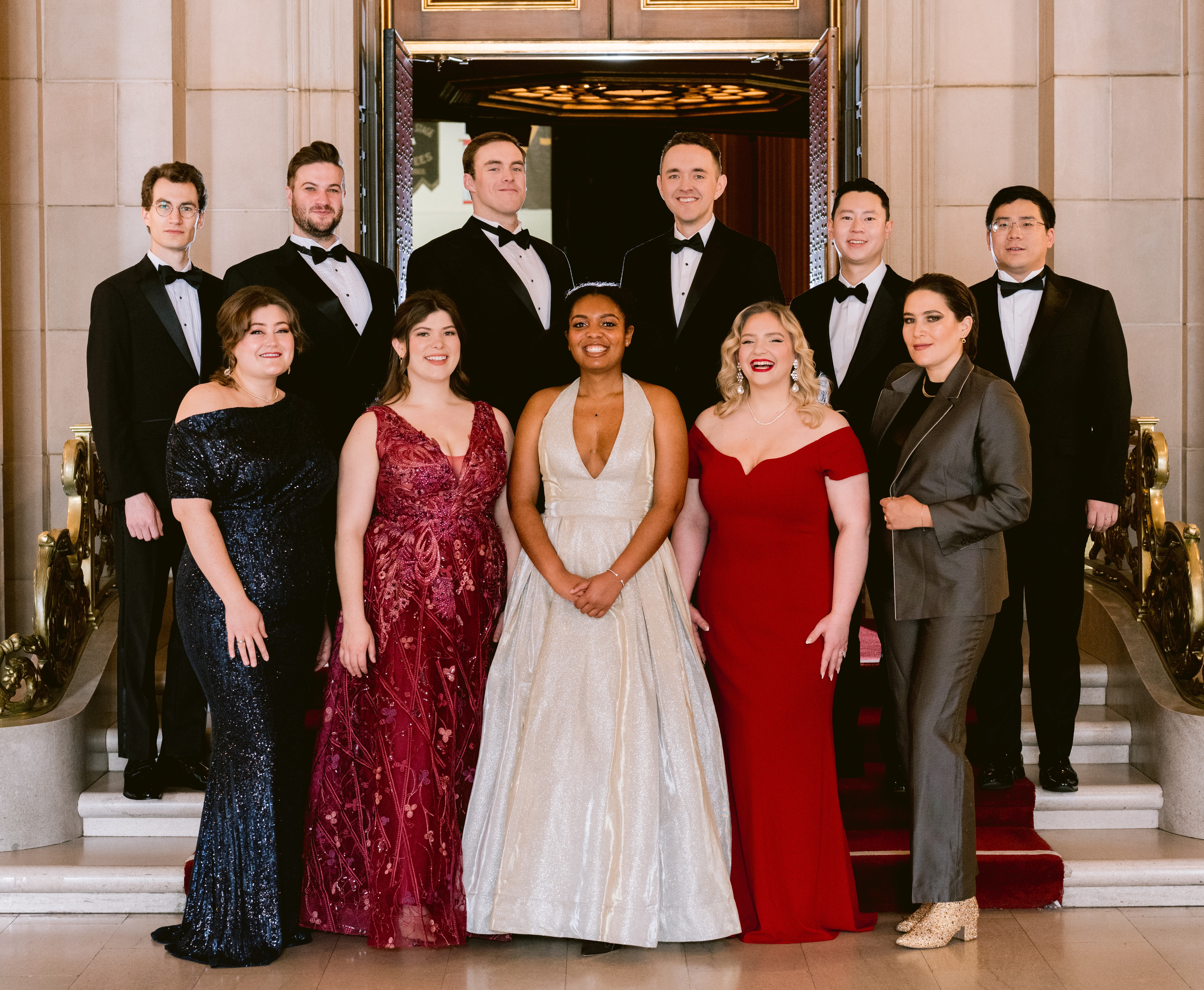 Group photo of individuals standing on stage in fancy attire