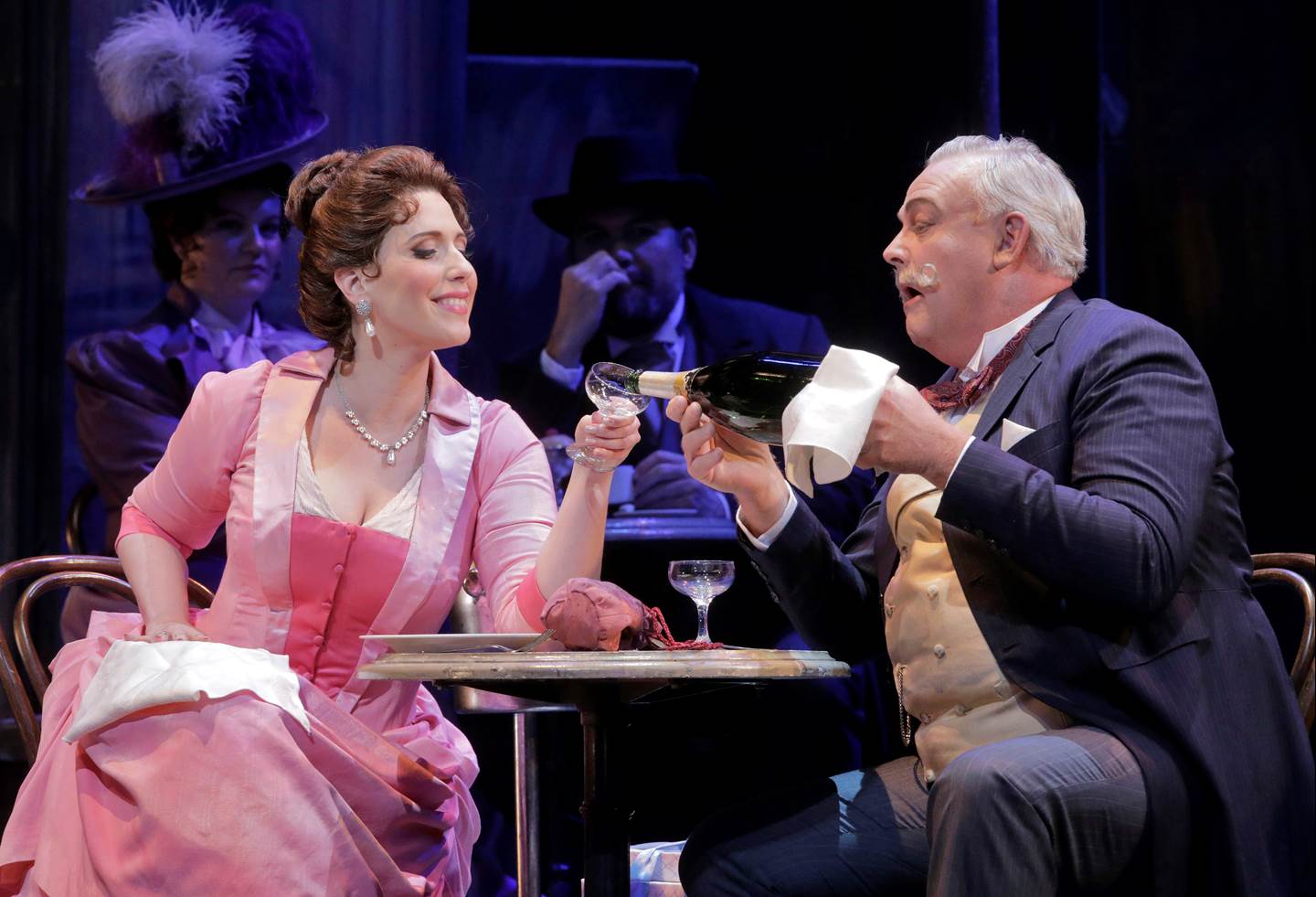 A man pouring champagne into the glass of a woman sitting at the table with him.