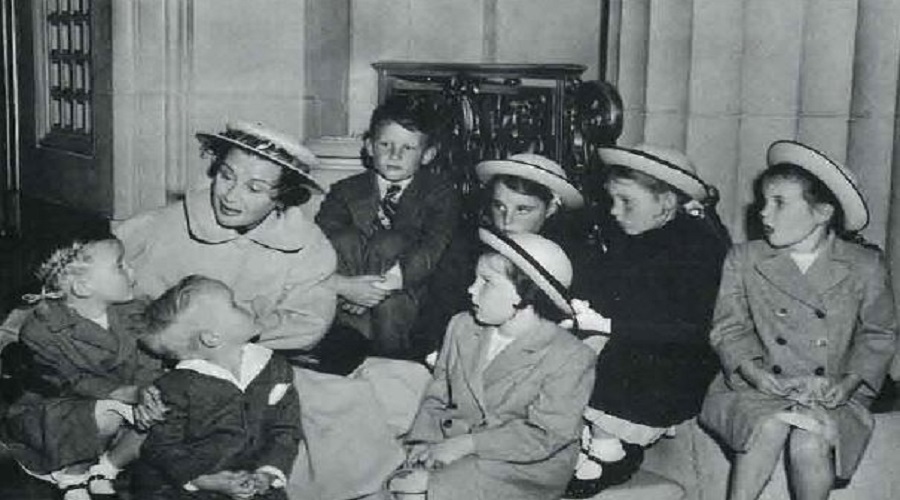 Bland and white photo of young students touring the Opera House with their teacher 