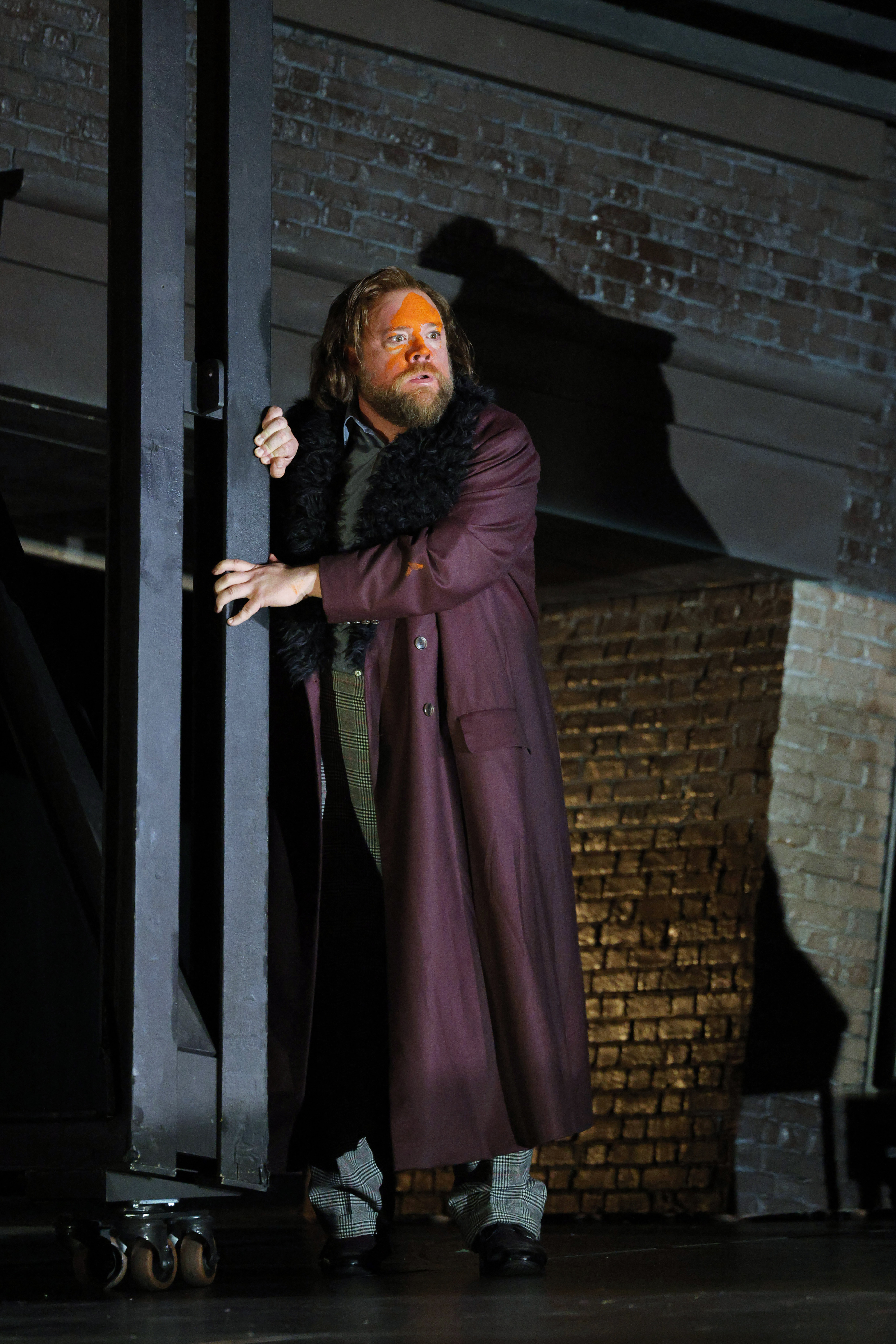 man with purple coat holding on to building