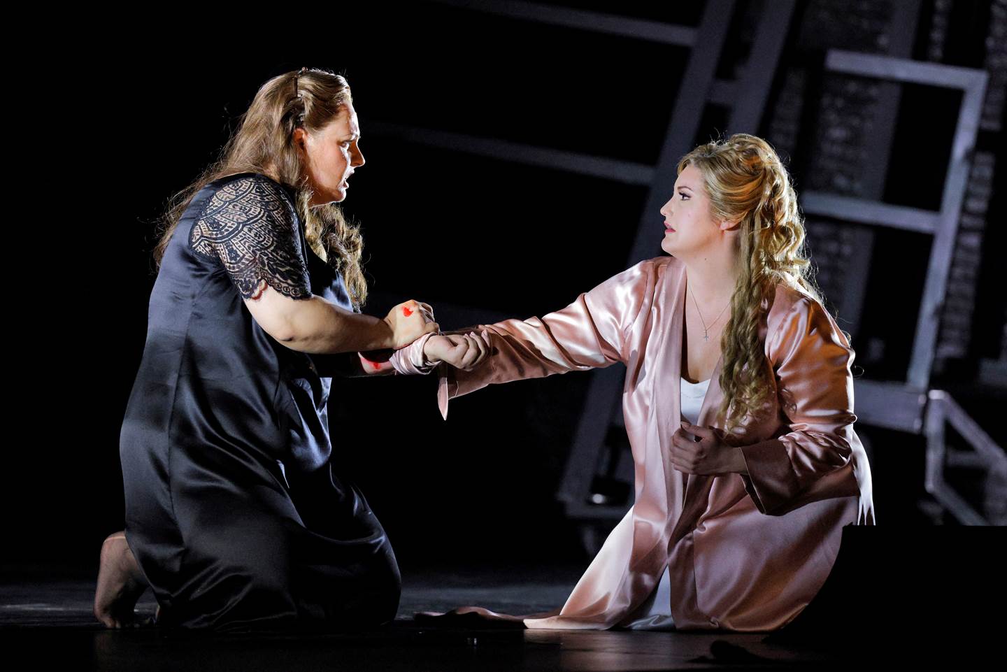 two women kneeling on stage embracing