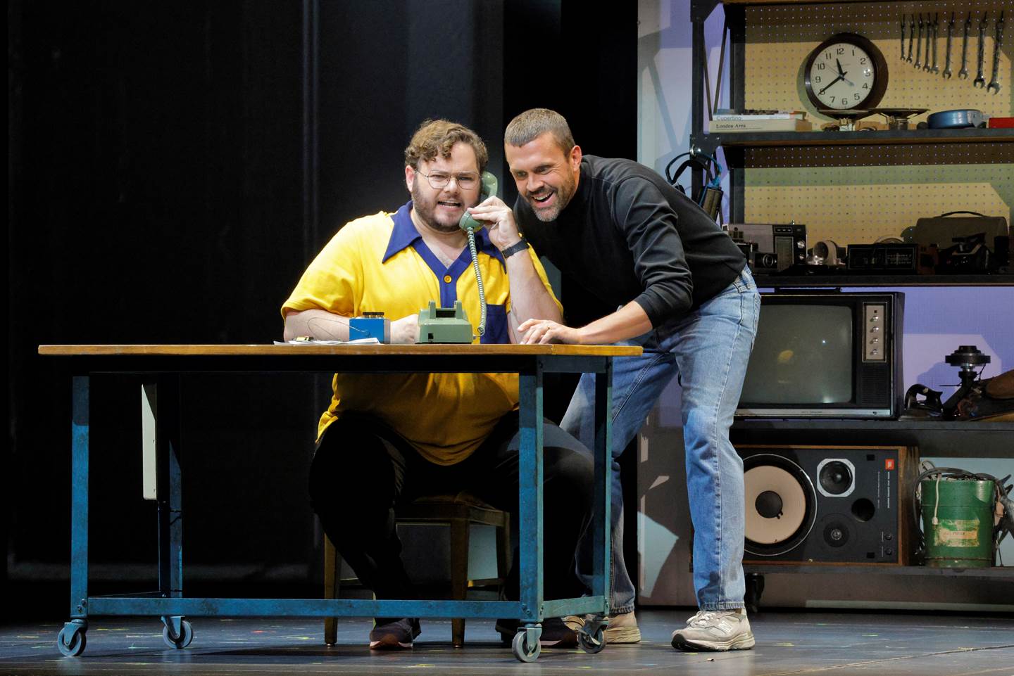 man in garage on phone with other man standing behind him