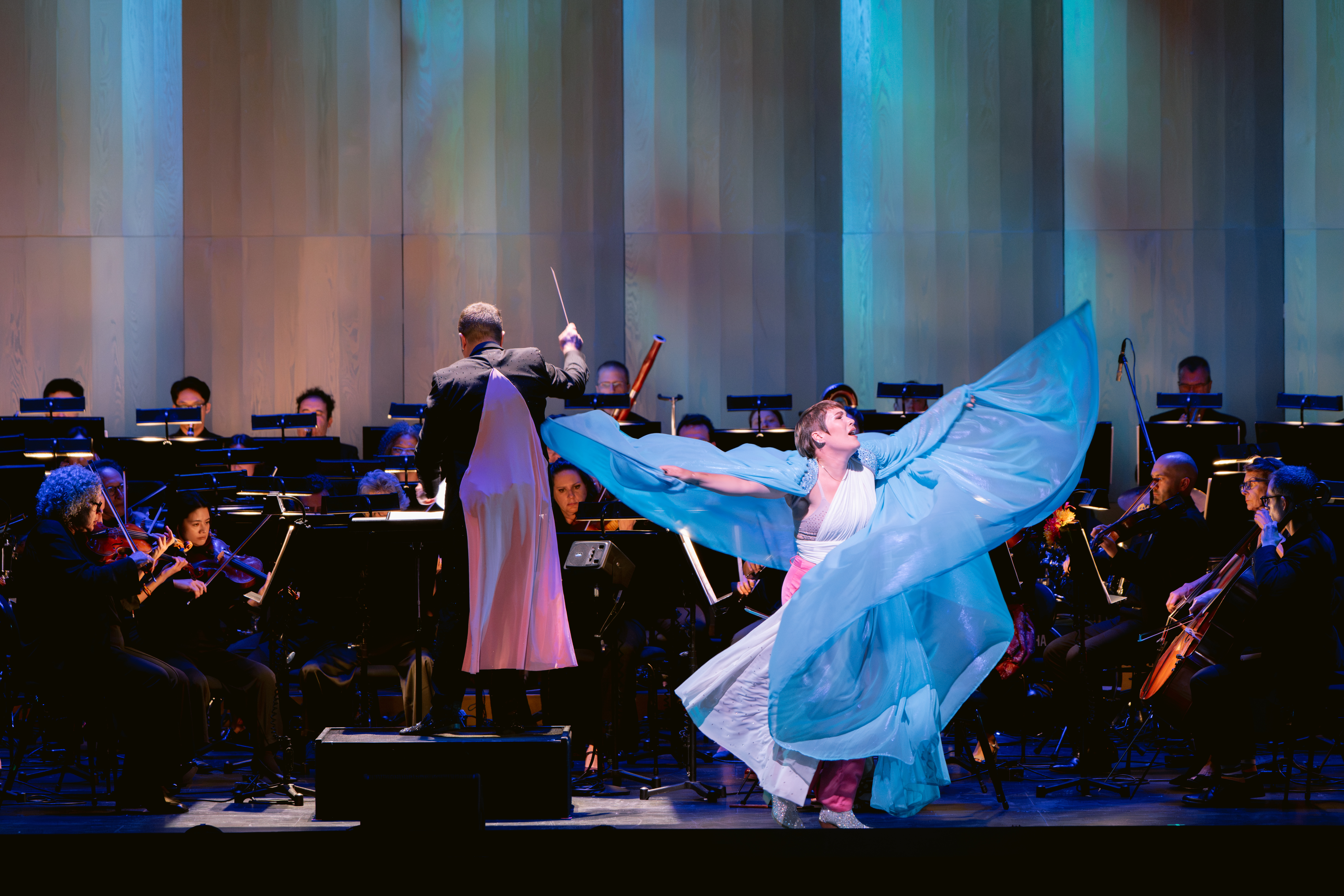 A singer in a flowing white and blue dress performs with the San Francisco Opera Orchestra during the 2026 Pride Concert.